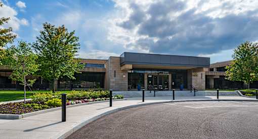 A modern building with a grey roof and a glass entrance. at The Residences at Tesson Ridge Apartments, Missouri