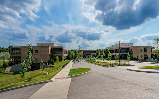 A large building complex with a parking lot in front. at The Residences at Tesson Ridge Apartments, Saint Louis, MO, 63128