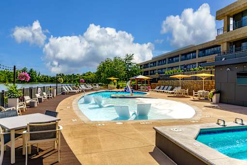 A large outdoor pool area with a hot tub and lounge chairs at The Residences at Tesson Ridge Apartments, Saint Louis, Missouri