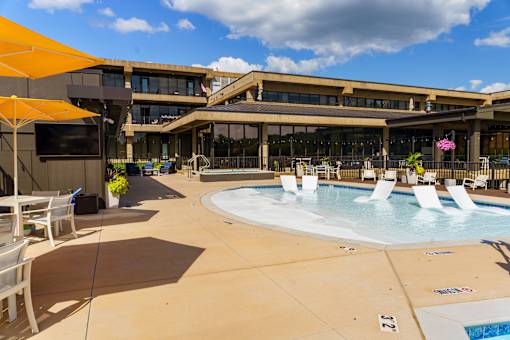 A large outdoor pool area with sun loungers and a building in the background. at The Residences at Tesson Ridge Apartments, Missouri, 63128