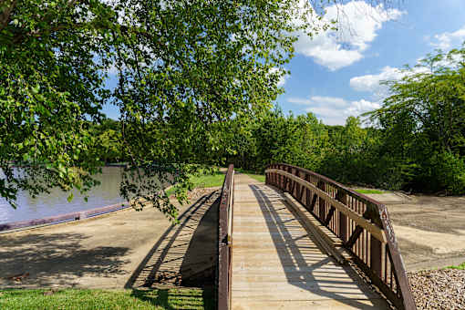 A bridge over a river with trees on the left at The Residences at Tesson Ridge Apartments, Saint Louis, MO, 63128