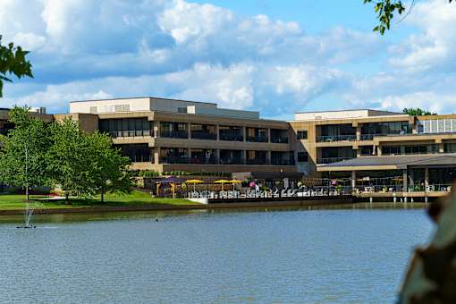 A large building with a lake in front of it. at The Residences at Tesson Ridge Apartments, Saint Louis, 63128