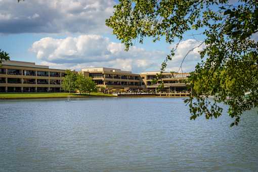 A body of water with a building in the background and a tree branch in the foreground. at The Residences at Tesson Ridge Apartments, Missouri
