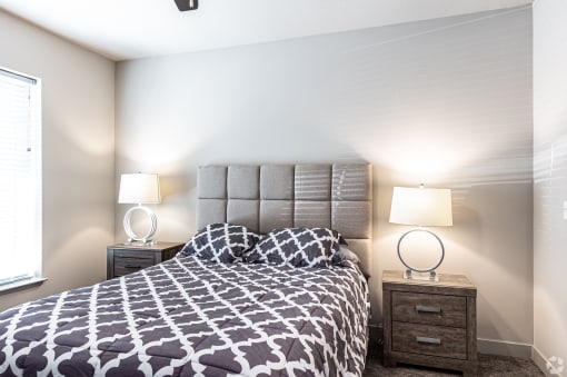 a bedroom with a bed and two lamps and a window