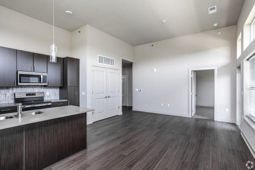 an empty kitchen and living room with wood flooring and white walls