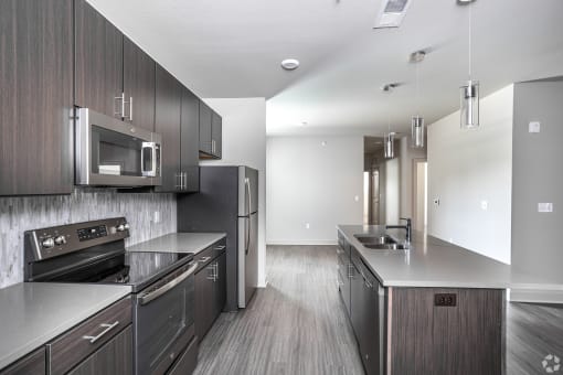 an empty kitchen with stainless steel appliances and wooden cabinets