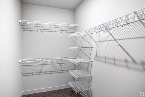 the walk in closet of a studio apartment with wire shelving