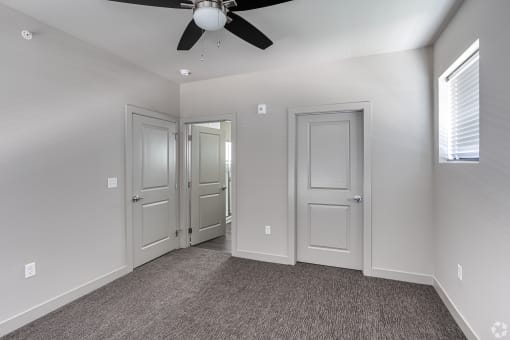 an empty room with three doors and a ceiling fan
