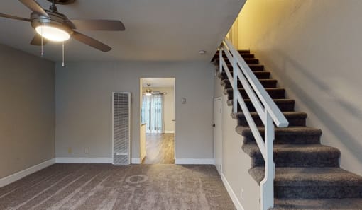 a living room with stairs and a ceiling fan