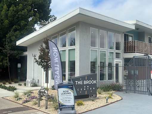 A sign for The Brook on Center in front of a building.