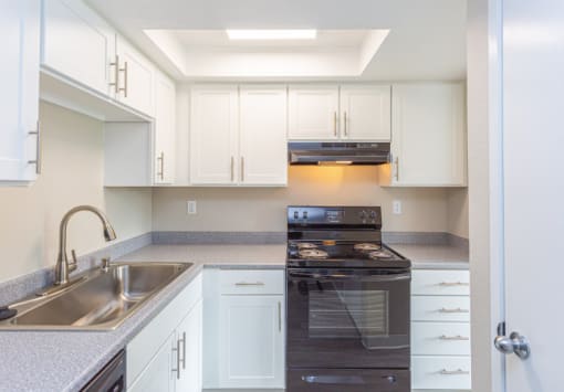a kitchen with white cabinets and black appliances