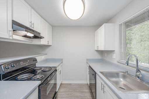 A kitchen with white cabinets and a stove top oven.