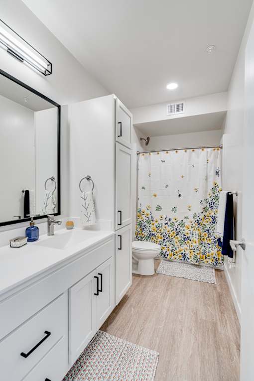 A white bathroom with a floral shower curtain. at The Shale, Minneapolis, MN