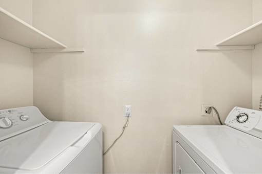 Two white washing machines in a laundry room.