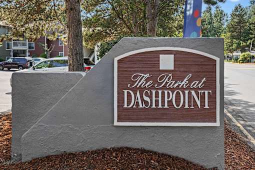 A sign that says "The Park at Dashpoint" is in front of a tree.