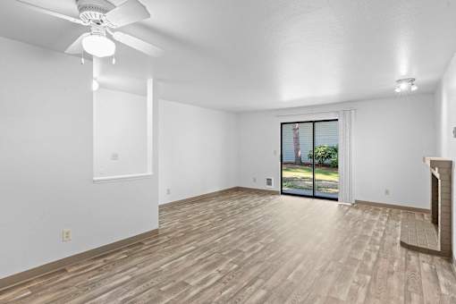 A room with a ceiling fan and sliding glass doors.