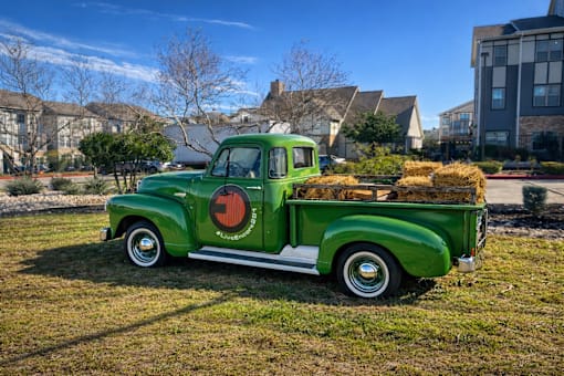 A green truck with a red logo is parked on a grassy area.
