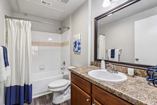 A bathroom with a white toilet, a sink, and a shower with a blue curtain.