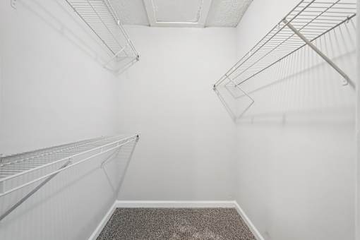 Empty walk-in closet with white walls and shelving.