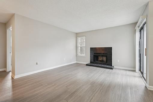 A large empty room with a fireplace and wood flooring.