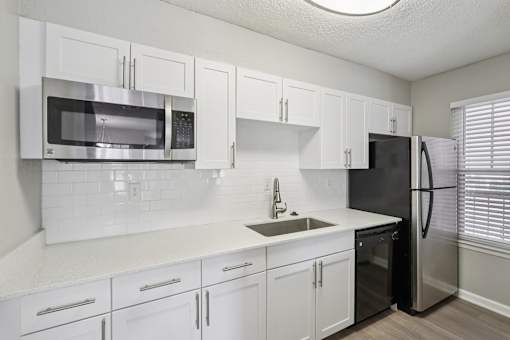 A kitchen with white cabinets and a black refrigerator.