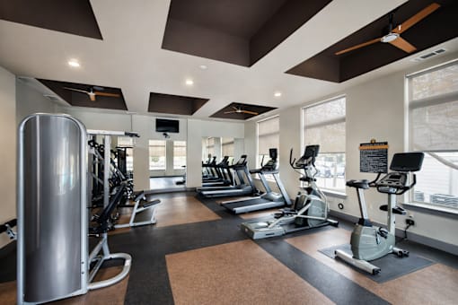 A gym with treadmills, elliptical machines, and a weight machine.