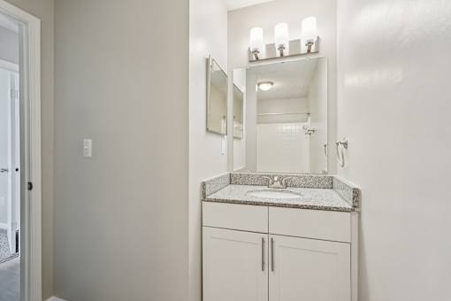 A bathroom with a sink, mirror, and cabinets.