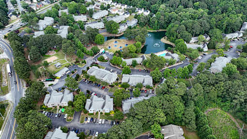 A bird's eye view of a residential area with houses, roads, and a lake.