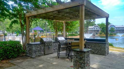 A covered patio with a grill and a table with chairs