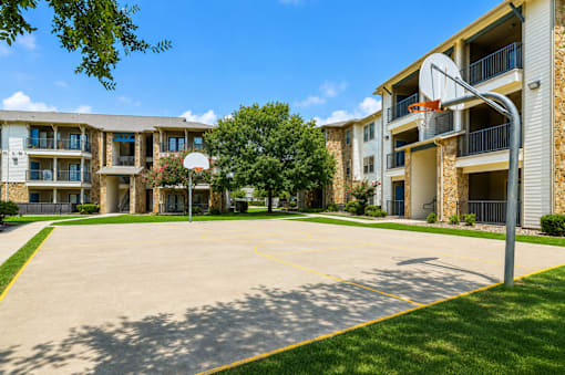 A basketball court is located in front of apartment buildings.