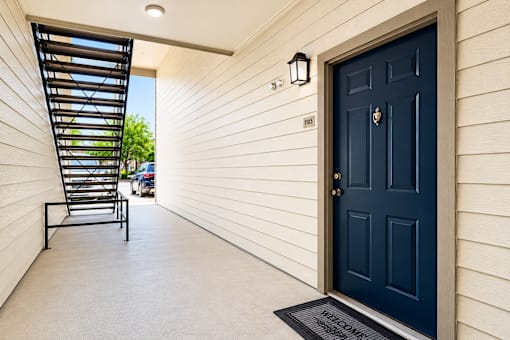 A black door with a mailbox on the side of a white house.
