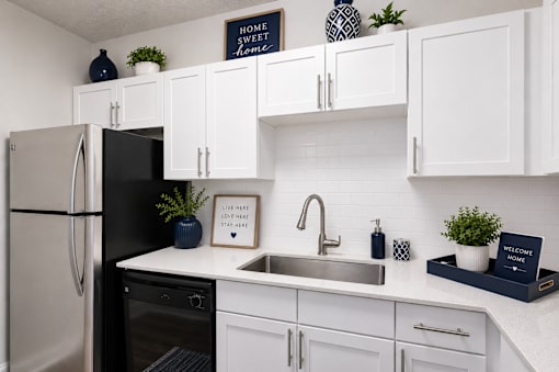 A kitchen with white cabinets and a black fridge.