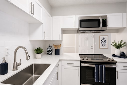 A modern kitchen with white cabinets and a black oven.