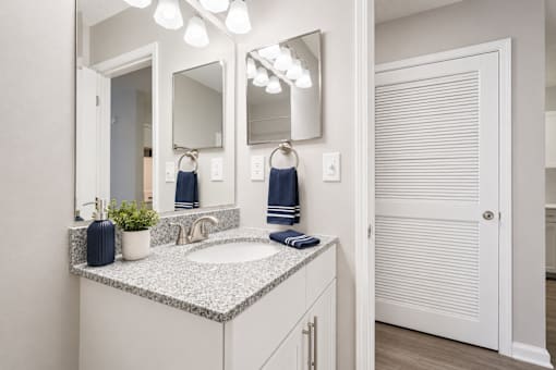 A bathroom with a sink, mirror, and towel rack.