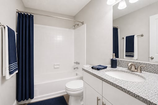 A bathroom with a white toilet, a white sink, and a white bathtub with a blue shower curtain.