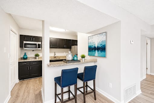 A kitchen with a bar stool and a painting on the wall.