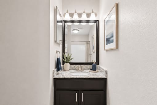A bathroom with a sink, mirror, and cabinet.