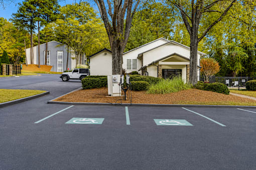 A parking lot with a white car and a white building in the background.