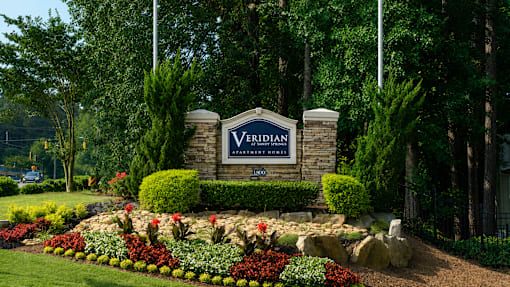 A sign that says "Verdian" in front of a flower bed.