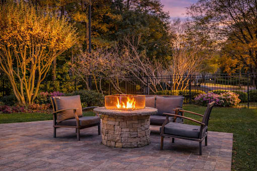 A fire pit in the middle of a patio surrounded by chairs.