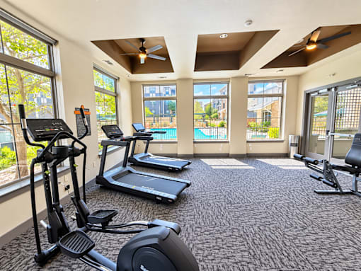 A spacious gym with treadmills, elliptical machines, and a stationary bike.