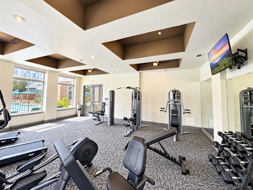 A gym with a variety of equipment including treadmills, weights, and exercise machines.