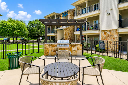 A patio with a table and chairs is surrounded by a black fence.