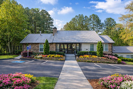 Our leasing office exterior filled with vibrant flowers and trees on a spring morning.