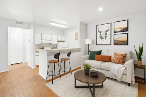 A living room with a white couch, a coffee table, and a kitchen area in the background.