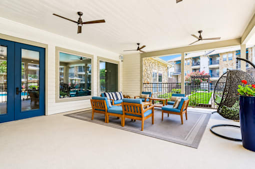 A patio with a blue chair set and a ceiling fan.