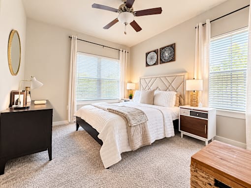 A bedroom with a large bed, a dresser, and a ceiling fan.