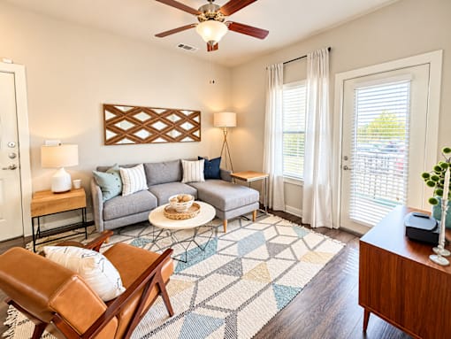 A living room with a grey couch, a wooden chair, and a rug.