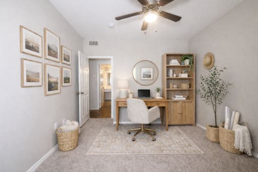 A room with a desk, chair, and pictures on the wall.