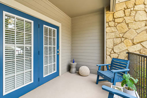 A blue chair sits on a porch next to a potted plant.
